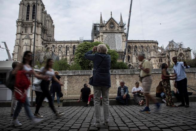 Varios turistas caminan junto a la catedral de Notre Dame de París (Francia) tras la creación de una nueva zona de seguridad para los visitantes, tras el incendio que el pasado lunes devastó parte del edificio.