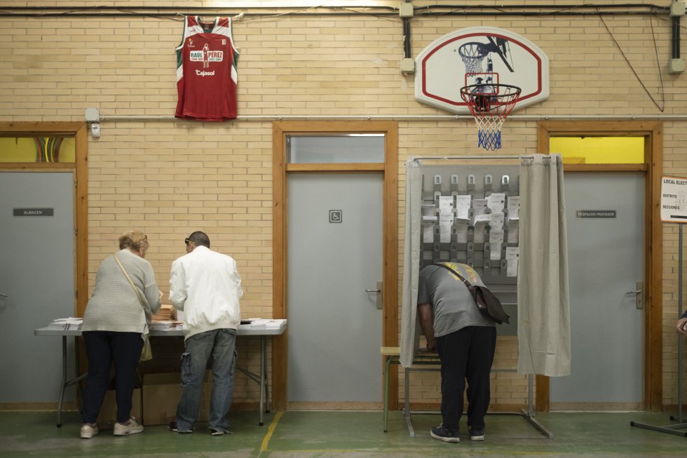 Varias personas acuden al colegio Miguel Hernández de Sevilla para ejercer su derecho a voto.
