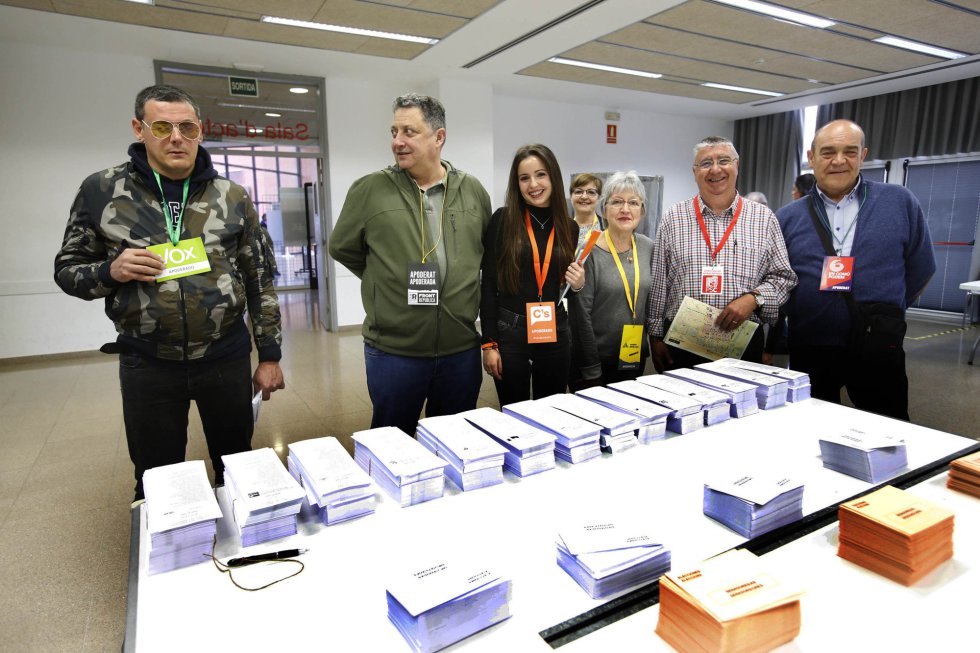 Apoderados de varios partidos políticos posan ante una mesa electoral en el Centro Cívico Montserrat Roig de terrasa.