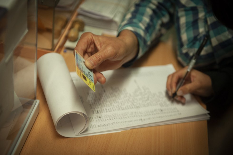 Un miembro de una mesa electoral comprueba el DNI de un votante en el colegio Pare Poveda de Barcelona.