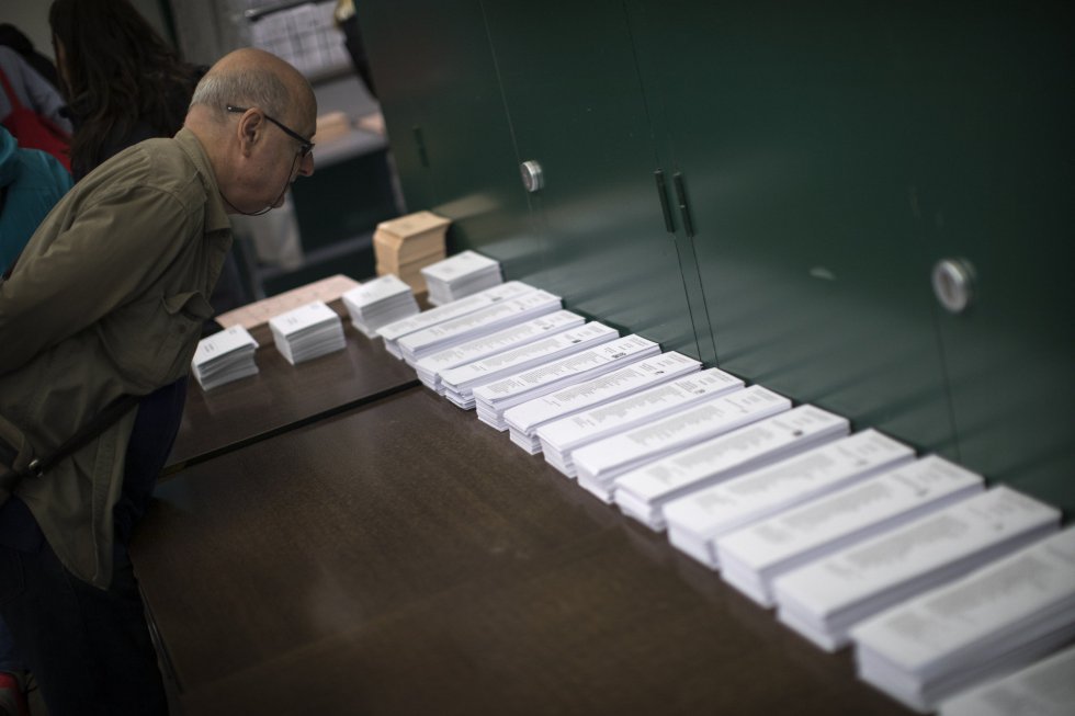 Un hombre observa las papeletas antes de votar en un centro electoral de Barcelona.