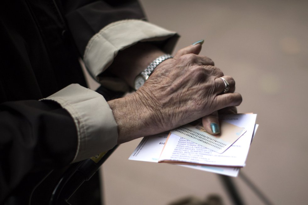 Una mujer sostiene sus papeletas junto con su documentación antes de votar en un centro electoral de Barcelona.