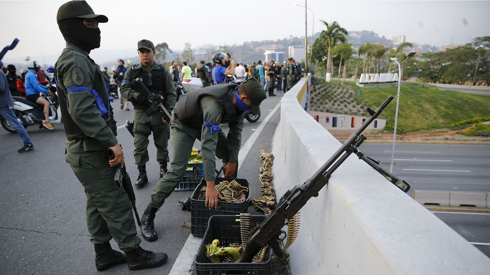 Los soldados de cinta azul se refugian en una autovía. (AP Photo/Ariana Cubillos)
