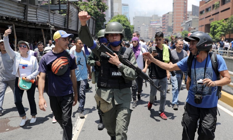 Un miembro de la Guardia Nacional Bolivariana se une a los manifestantes de la oposición durante las protestas en Caracas. (Reuters)
