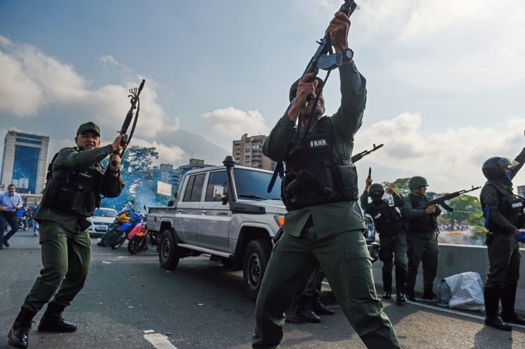 Miembros de la Guardia Nacional que se sumaron al levantamiento disparan al aire a modo de disuasión (Photo by Federico PARRA / AFP)