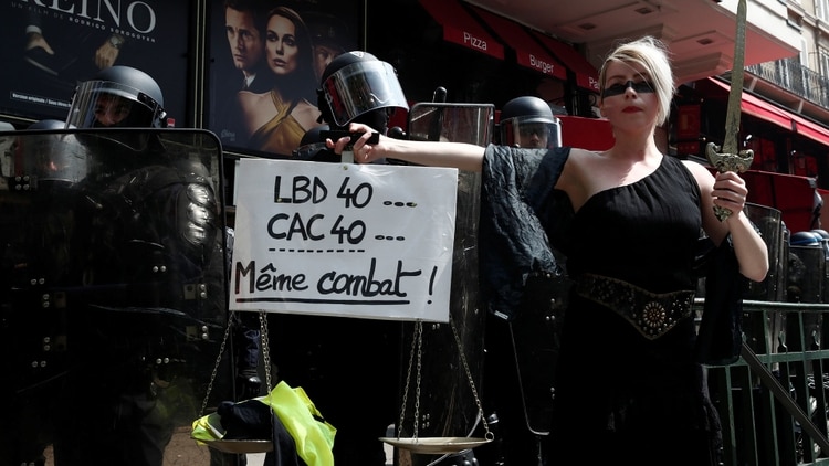 Una manifestante sostiene una balanza y una pancarta que dice “LBD40, CAC40 la misma lucha” frente a la policía antidisturbios francesa durante una manifestación (Reuters)