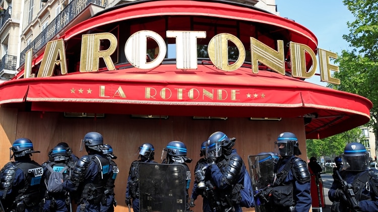 La policía antidisturbios francesa se para frente a los paneles de madera que protegen el restaurante La Rotonde, muy identificado con Emmanuel Macron (Reuters)