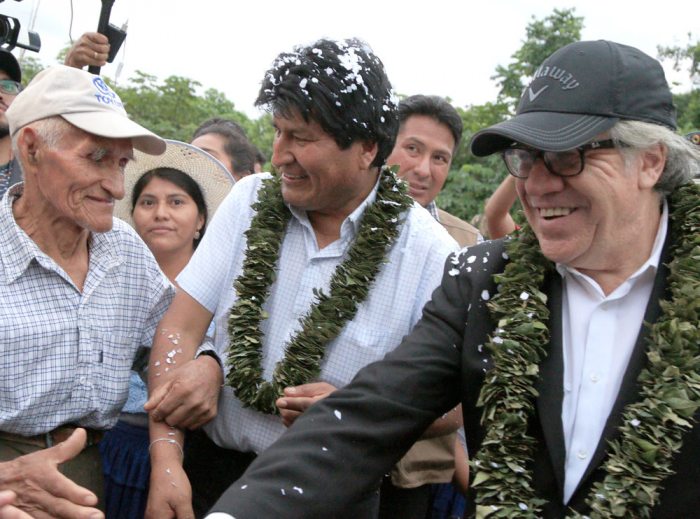 LUIS ALMAGRO JUNTO A EVO MORALES DURANTE LA VISITA AL CHAPARE; LUCIERON GIRNALDAS ELABORADAS CON LA HOJA DE COCA. LA IMAGEN MUESTRA EL MOMENTO EN QUE SALUDABAN A LOS POBLADORES DEL LUGAR. FUE EL SÁBADO PASADO.