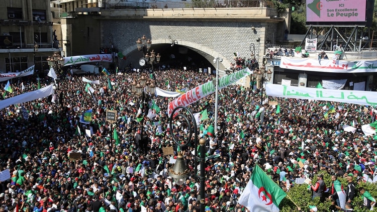 Manifestantes portan banderas y pancartas nacionales durante una protesta para exigir la renuncia del Presidente Abdelaziz Bouteflika, en Argelia, 29 de marzo de 2019. (Reuters)