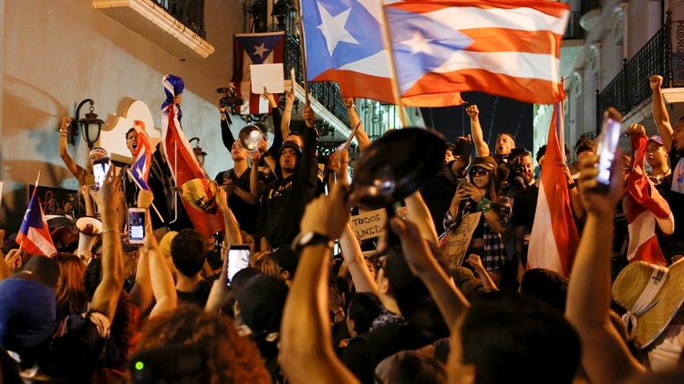 Manifestantes cantan y ondean banderas puertorriqueñas durante las protestas que pedían la renuncia del gobernador Ricardo Rosselló el 23 de julio de 2019 (REUTERS/Marco Bello)