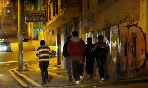 Un grupo de jóvenes caminan por una de las calles casi oscuras de La Paz. 
