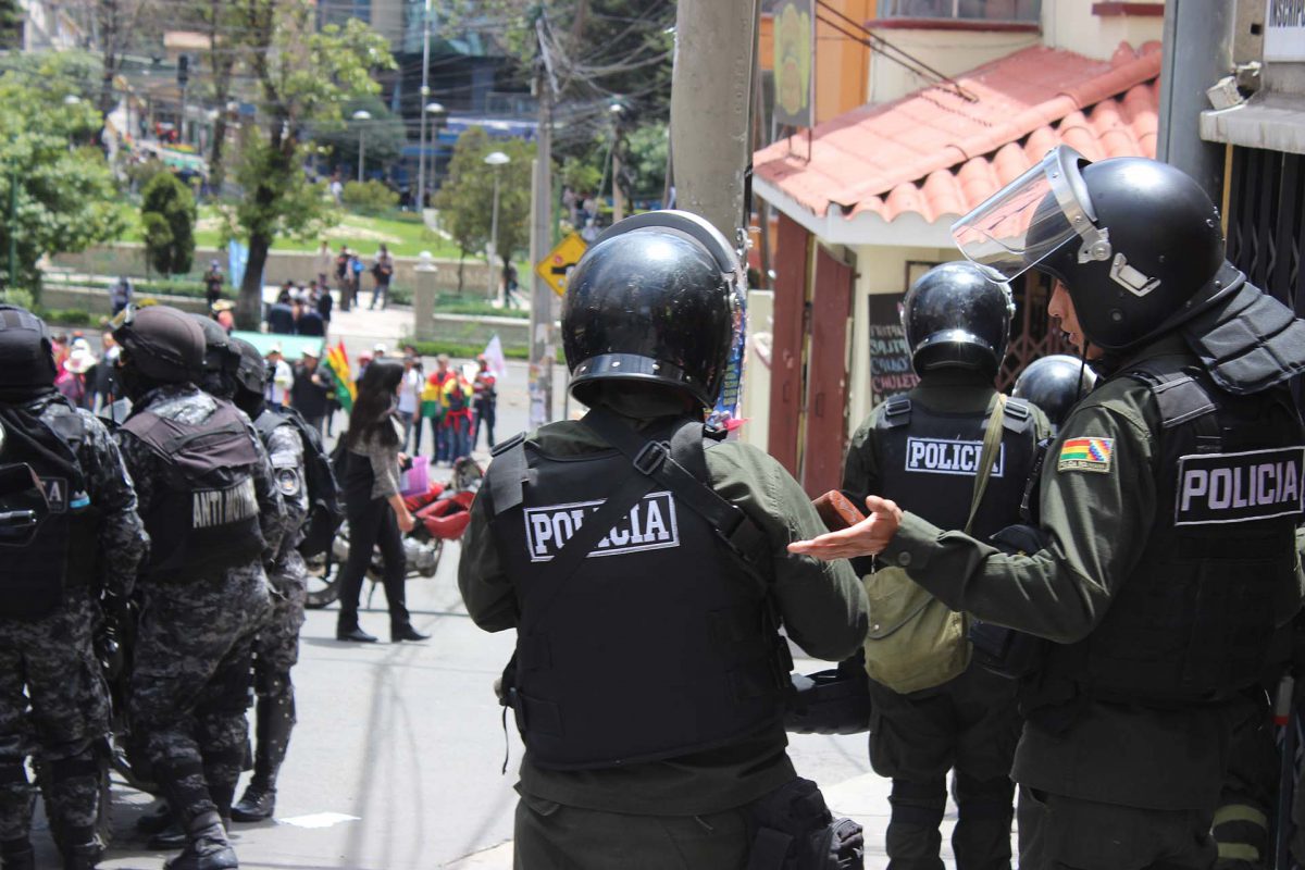 Un grupo de policías antidisturbios se sitúa frente a manifestantes que bloquean una calle en el centro de La Paz (EFE/Luis Ángel Reglero)