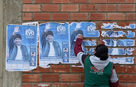 Una mujer despega carteles del expresidente boliviano Evo Morales este lunes en La Paz. Foto: AFP
