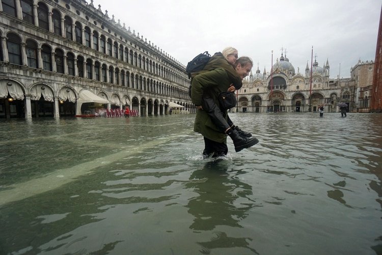 Un hombre carga a una mujer a través de las aguas de la inundación en Piazza San Marco (Plaza de San Marcos) en Venecia, Italia, 12 de noviembre de 2019. (EFE)