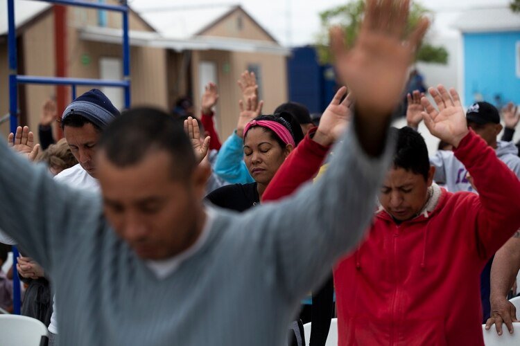 En esta imagen del 12 de octubre de 2019, cubanos rezando en un refugio para migrantes en Reynosa, México. En años anteriores, los migrantes pasaban con rapidez por esta tierra de cárteles. Ahora, con las nuevas políticas migratorias de Donald Trump, se quedan ahí durante meses mientras esperan sus citas en las cortes estadounidenses, varados en las fauces del crimen organizado. (AP Foto/Fernando Llano)