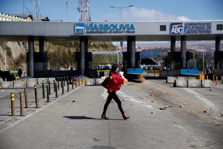 Una mujer camina en una calle bloqueada por manifestantes favorables al ex presidente Evo Morales en El Alto (REUTERS/David Mercado)