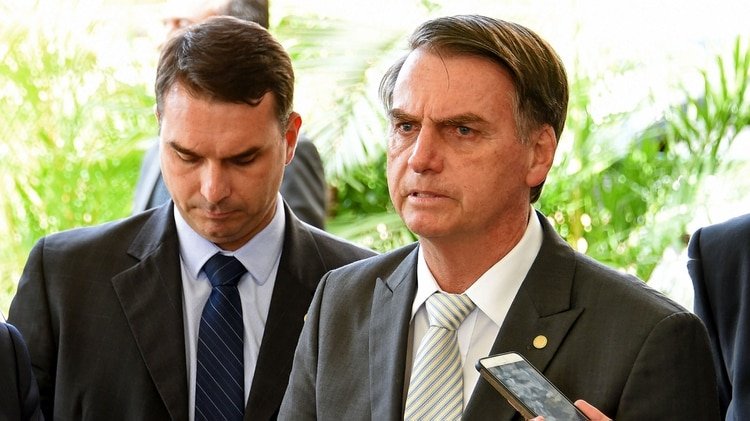 El presidente electo de Brasil, Jair Bolsonaro (R), junto a su hijo y senador Flavio Bolsonaro, y su designado Ministro de Infraestructura, Tarcisio Gomes de Freitas (L), se prepara para hablar ante la prensa en la sede del gobierno de transición en Brasilia, el 27 de noviembre de 2018. (Foto por EVARISTO SA / AFP) 