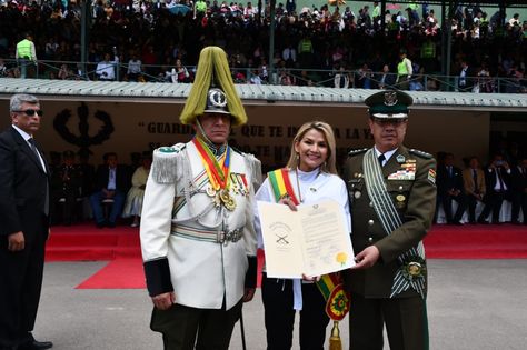 La presidenta Jeanine Áñez muestra la distinción que le otorgo Anapol, cuyo director, coronel Dayler Zurita, está con traje claro.