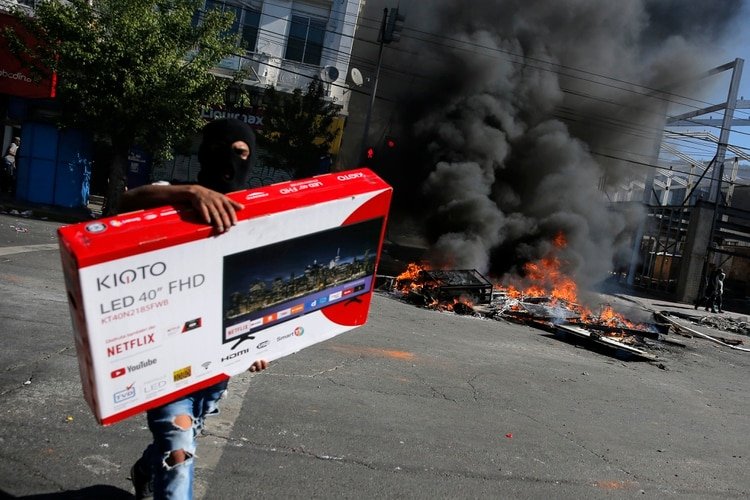 A los Carabineros les llamó la atención que gente que participaba de saqueos llegaba a los comercios a bordo de vehículos de alta gama (AFP)