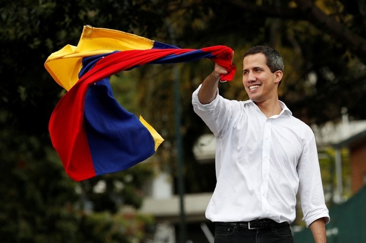 El líder de la oposición venezolana Juan Guaidó, a quien muchos países han reconocido como el legítimo gobernante interino del país, ondea la bandera venezolana en una reunión con partidarios cerca de la embajada de Bolivia en Caracas, Venezuela, el 16 de noviembre de 2019. (REUTERS)