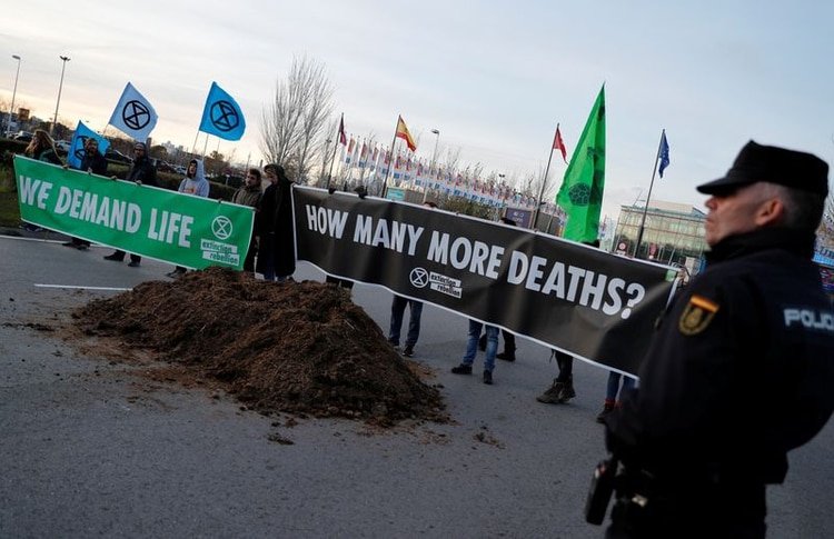 Activistas contra el cambio climático de Extinction Rebellion sostienen letreros luego de descargar un camión lleno de excremento de caballo frente al recinto en el que se realiza la Conferencia de Cambio Climático de Naciones Unidas COP25 en Madrid, España. 14 de diciembre, 2019. REUTERS/Nacho Doce