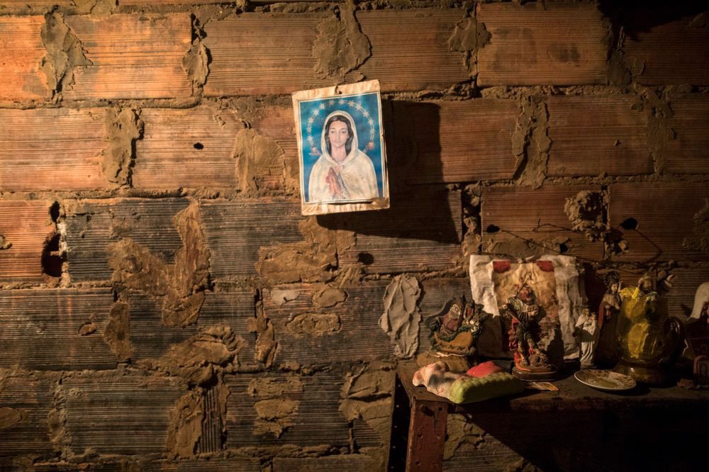Una imagen de la Virgen María cuelga de una pared de ladrillos al lado de la habitación donde se prepara el cadáver de Teresa Jiménez después de su muerte por causas naturales a la edad de 91 años en Maracaibo, Venezuela, el 17 de noviembre de 2019 (AP)
