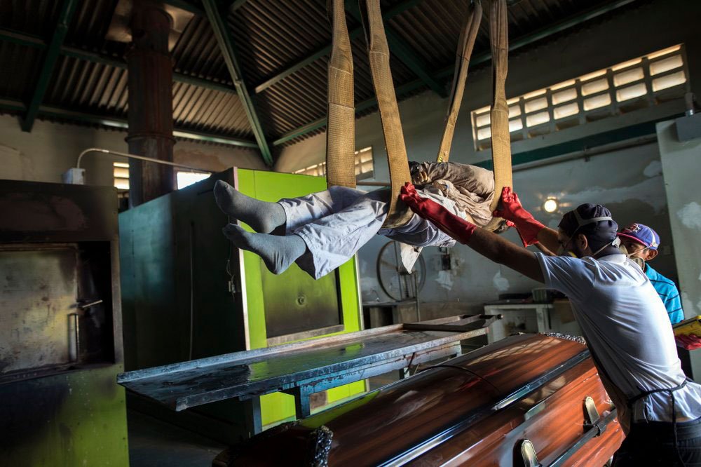Los trabajadores del cementerio levantan un cadáver de un ataúd a una placa de metal mientras preparan el cuerpo para la cremación en un cementerio en Maracaibo, Venezuela, el 27 de noviembre de 2019 (AP)
