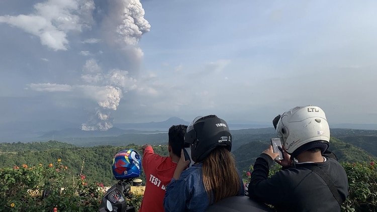 La gente toma fotos de una explosión freática desde el volcán Taal visto desde la ciudad de Tagaytay en la provincia de Cavite, al suroeste de Manila, el 12 de enero de 2020. (Foto de Bullit MARQUEZ / AFP)