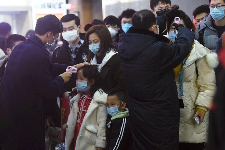 Personal verifica la temperatura corporal de los pasajeros que llegan del tren de Wuhan a Hangzhou, en la estación de tren de Hangzhou, antes del Año Nuevo Lunar chino el 23 de enero de 2020 (China Daily via REUTERS)