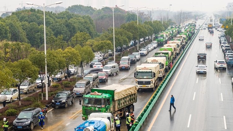 Los camiones esperan su turno para cargar la tierra que será extraída del terreno donde se construirá el centro de salud (Foto de STR/ AFP/ China OUT) 
