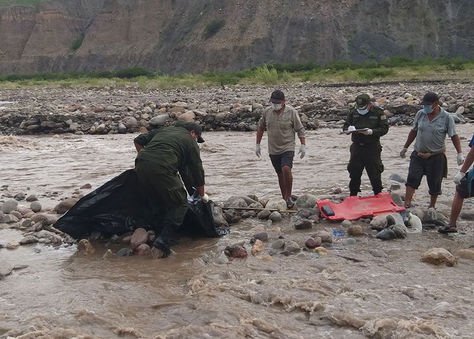 Un efectivo de la Policía y algunos voluntarios proceden a levantar el cuerpo de la joven. Foto: Radio Perla Andina.