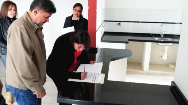 Una beneficiaria firma los documentos de adquisición del departamento. | Daniel James