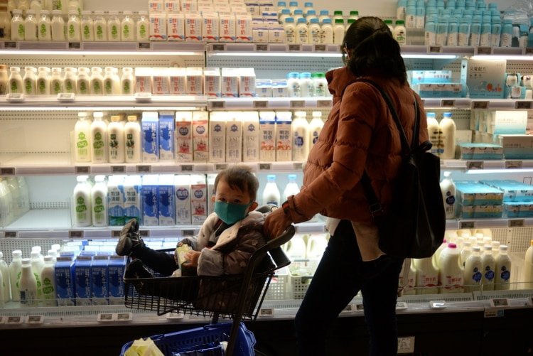 Una mujer y su pequeño hijo usan mascarillas mientras hacen sus compras en el supermercado (REUTERS/Tingshu Wang)