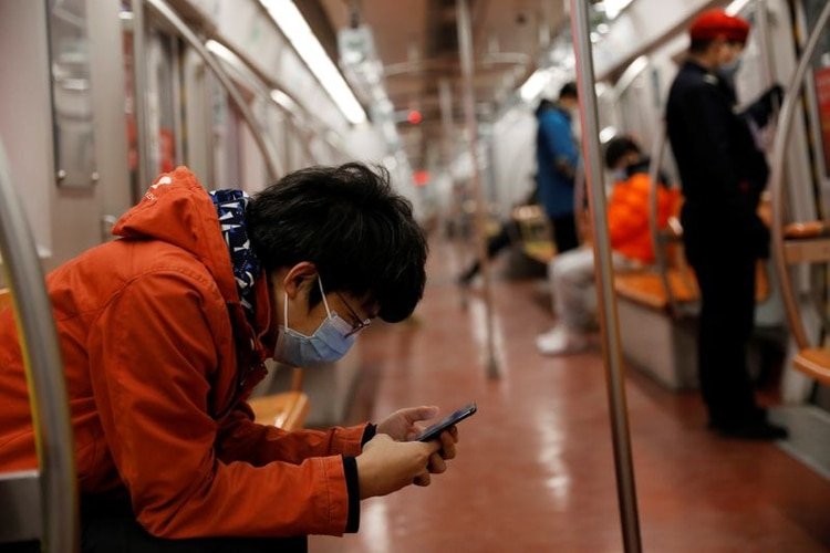 Un hombre con mascariila revisa su teléfono móvil mientras viaja en metro por la mañana después del prolongado día festivo del Año Nuevo Lunar causado por el novedoso brote de coronavirus, en Pekín, China, el 10 de febrero de 2020. REUTERS/Carlos Garcia Rawlins