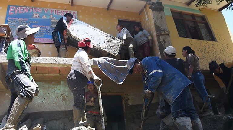 Una familia saca el lodo que invadió su casa el viernes por la riada del río Taquiña y traslada su refrigerador al segundo piso, en la calle 16 de Julio. | Daniel James