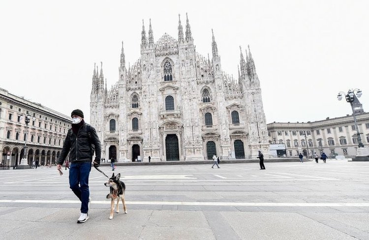 Un hombre con mascarilla con un perro en la plaza del Duomo, Milán, Italia, 10 marzo 2020. REUTERS/Flavio Lo Scalzo