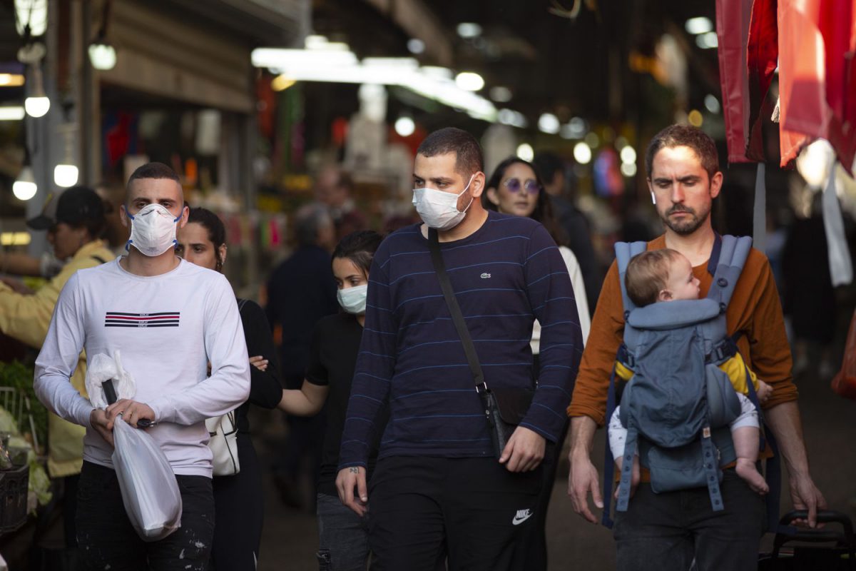Un grupo de vecinos de Tel Aviv, algunos con mascarillas, pasean por las calles de la ciudad israelí.
