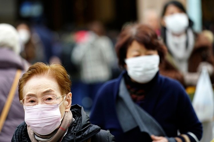 Peatones con mascarillas de protección en un distrito comercial de Tokio, el jueves 16 de enero de 2020. (AP Foto/Eugene Hoshiko)