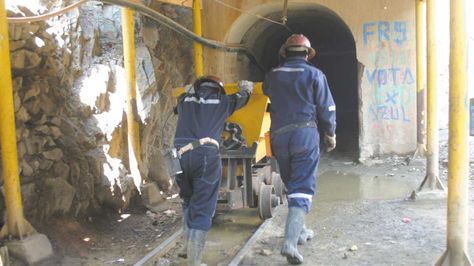 Dos trabajadores mineros se internan a uno de los socavones de la mina estatal Huanuni.