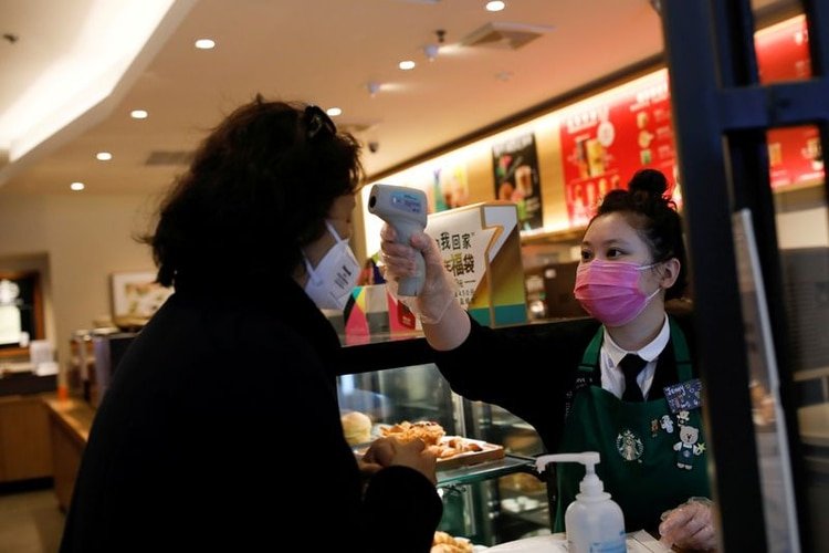 FOTO DE ARCHIVO. Una trabajadora usa un termómetro para verificar la temperatura de un cliente cuando ingresa a una tienda de Starbucks, mientras el país se ve afectado por un brote del nuevo coronavirus, en Pekín, China. 30 de enero de 2020. REUTERS/Carlos García Rawlins.