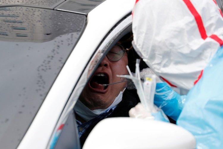 Personal médico utiliza un hisopo para tomar muestras de un conductor en el centro de pruebas de la Universidad de Yeungnam en Daegu, Corea del Sur, el 3 de marzo de 2020. (REUTERS/Kim Kyung-Hoon)