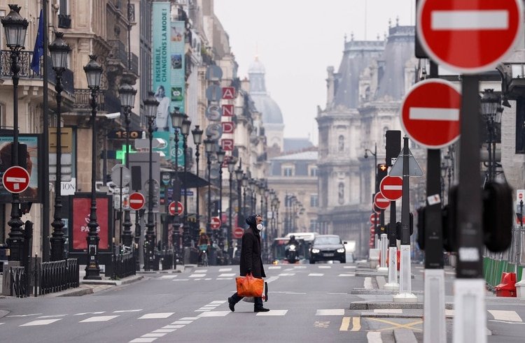 Un hombre con una máscara protectora cruza la desierta Rue de Rivoli en París el 18 de marzo de 2020 (REUTERS/Christian Hartmann)