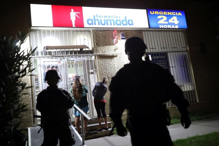 Soldados custodian una farmacia en la ciudad de Santiago de Chile el 20 de marzo de 2020 después de que el presidente Sebastián Piñera ordenara el estado de catástrofe, debido al brote de la enfermedad del coronavirus (REUTERS/Pablo Sanhueza)