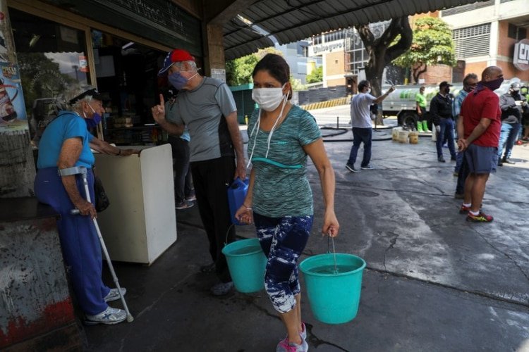 Una mujer lleva dos cubos de agua en una calle en medio de una cuarentena para contener la propagación de los casos de coronavirus (COVID-19) en Caracas, Venezuela Marzo 23, 2020. REUTERS/Manaure Quintero