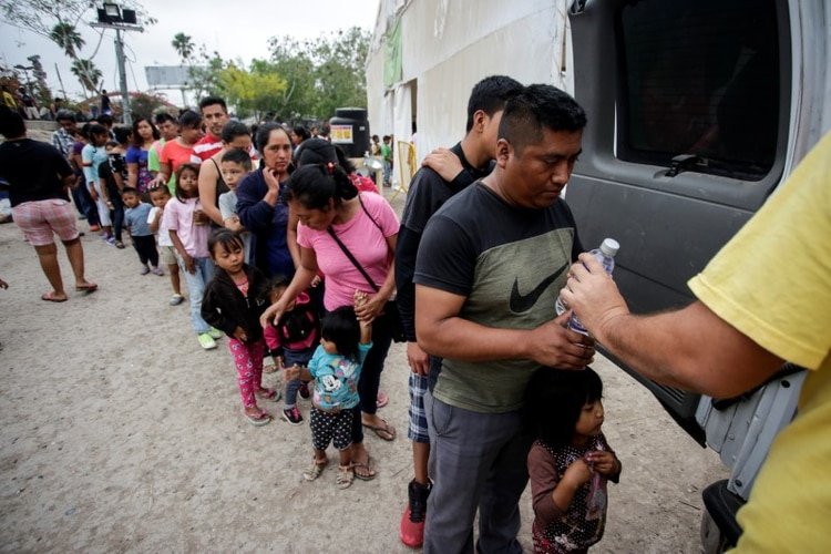 Migrantes se forman para recibir agua embotellada en un campamento de más de 2,000 personas que buscan asilo en EEUU, mientras las autoridades se preparan para responder al brote de coronavirus en Matamoros, México. 22 de marzo de 2020. REUTERS/Daniel Becerril