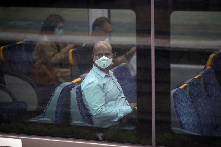 Un viajero que usa una máscara facial se sienta en un tren durante la hora pico de la mañana después de que Nueva Gales del Sur comenzó a cerrar negocios no esenciales y avanzó hacia sanciones severas para forzar el autoaislamiento a medida que la propagación de la enfermedad por coronavirus (Reuters)