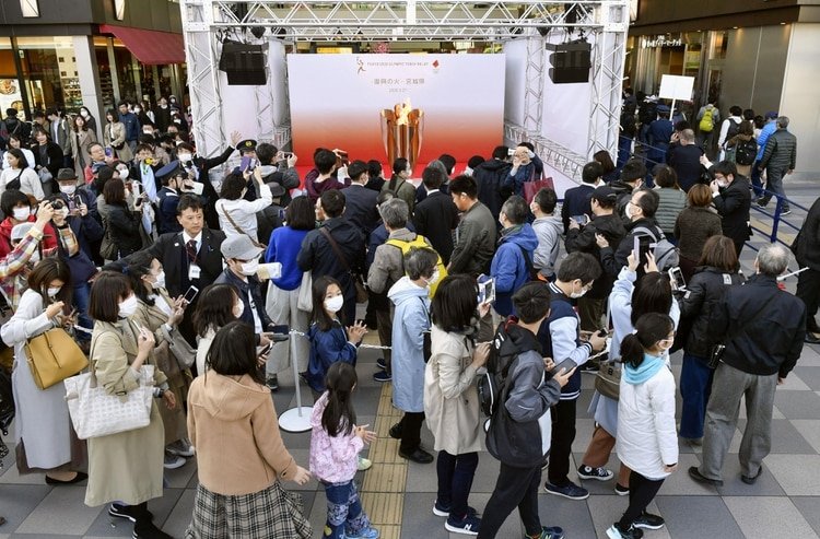 Las persona llevan máscaras protectoras y hacen cola mientras intentan ver el caldero olímpico en la estación de Sendai, prefectura de Miyagi, Japón, el 21 de marzo de 2020 (foto tomada por Kyodo. Crédito obligatorio Kyodo/via REUTERS)