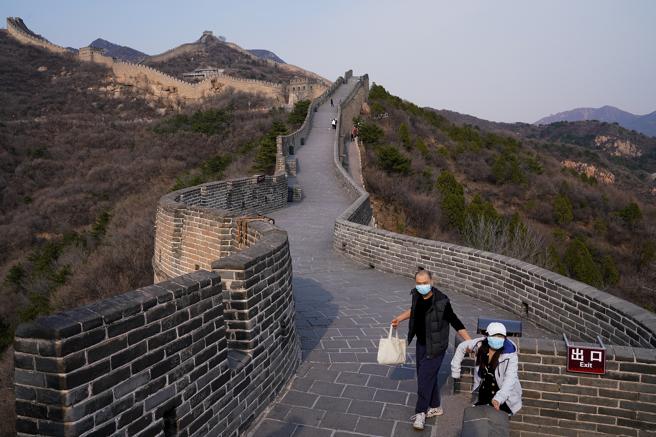 Dos turistas chinos protegidos con máscaras visitan la sección reabierta de la Gran Muralla China, el 24 de marzo