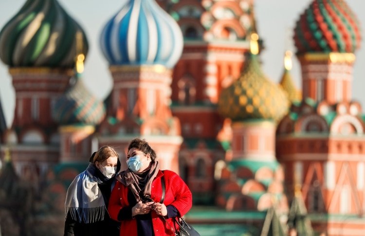 Women with protective masks, widely used as a preventive measure against coronavirus disease (COVID-19), walk across Red Square near the St. Basil