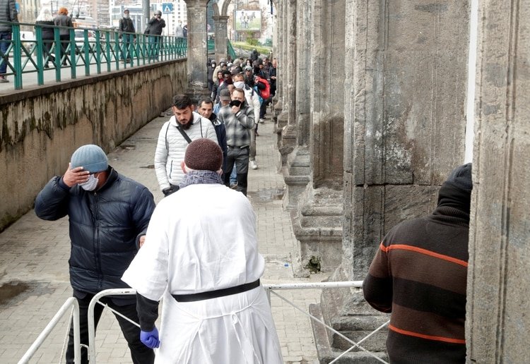 El sacerdote Francesco con una máscara facial y guantes protectores, entrega bolsas de comida a personas sin hogar y pobres, mientras continúa la propagación de la enfermedad por coronavirus (COVID-19), en Nápoles, Italia, el 27 de marzo de 2020. (REUTERS / Ciro De Luca)